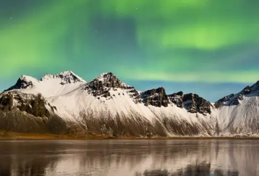 Northern Lights Over Hofn And Mountain Range Iceland.