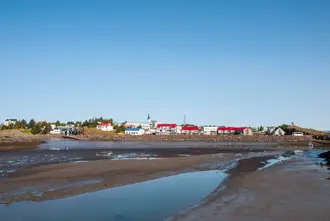 Borgarnes coastal village on a sunny day with colorful rooftops and reflections in low tide waters, framed by a clear blue sky, Iceland.