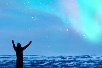  Silhouette of a person celebrating Northern Lights in Iceland.