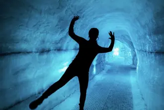 A visitor striking a playful pose inside the ice cave exhibit at the Perlan Museum in Reykjavik, Iceland.