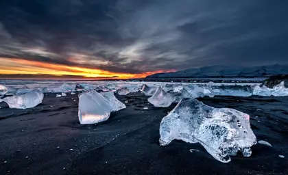 Glowing icebergs at sunset on Fellsfjara Diamond Beach in Iceland, highlighting the unique natural beauty of this must-see destination on Travel Reykjavik tours