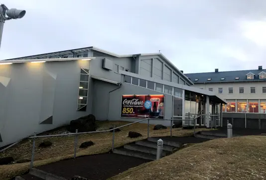 Exterior view of Laugarásbíó Cinema in Reykjavik with a Coca-Cola advertisement, showcasing Iceland's popular movie theater experience for tourists and locals.
