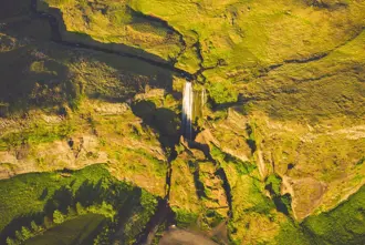 Aerial view of Gljúfrabúi Waterfall and surrounding mossy cliffs, showing its secluded location near the southern coast of Iceland.
