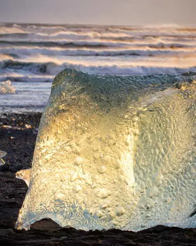 Glowing iceberg at sunset on Diamond Beach near Jökulsárlón Glacier Lagoon, Iceland