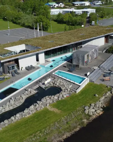 Aerial view of Fontana geothermal spa in Iceland, with outdoor pools surrounded by greenery and modern architecture, offering a unique relaxation experience.