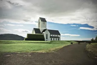 Scenic view of the historic Skalholt Church under cloudy skies, Iceland.