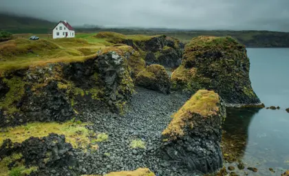 View of Arnarstapi cliffs and white house on the Snaefellsnes peninsula in Iceland.