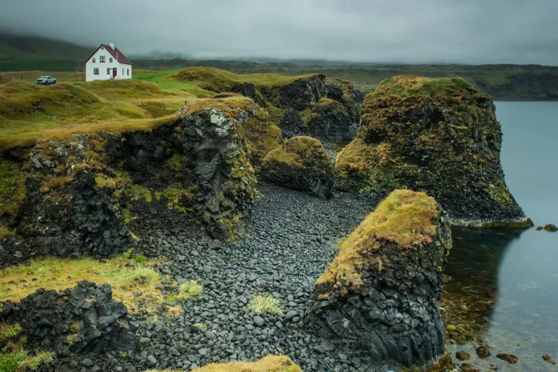 View of Arnarstapi cliffs and white house on the Snaefellsnes peninsula in Iceland.