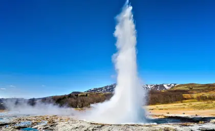 Eruption of Geysir hot spring in Iceland on a clear blue day, showcasing the natural geothermal beauty of the Golden Circle.