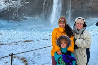 Family Of Travelers In Front Of Seljalandsfoss Waterfall, Visiting In Winter.