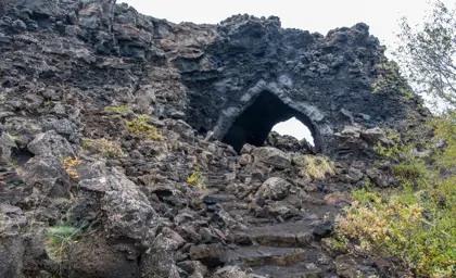 The church at Dimmuborgir lava field in Mývatn. A natural lava rock arch in Iceland, surrounded by rugged volcanic rocks and autumn foliage.
