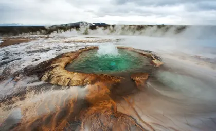 Bubbling Geysir hot spring in Iceland with vibrant colors and steam rising, part of the Golden Circle tour with Travel Reykjavik.