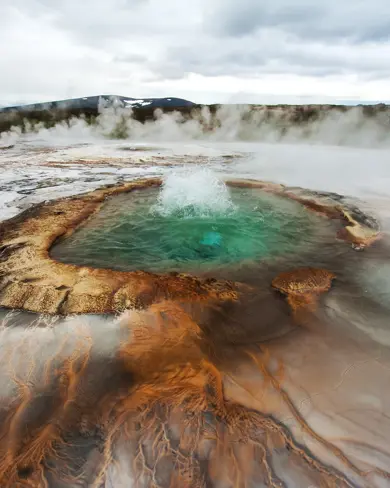Bubbling Geysir hot spring in Iceland with vibrant colors and steam rising, part of the Golden Circle tour with Travel Reykjavik.