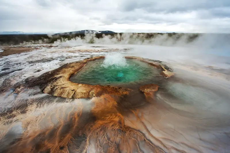 Bubbling Geysir hot spring in Iceland with vibrant colors and steam rising, part of the Golden Circle tour with Travel Reykjavik.