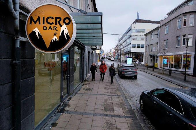 Street view of Micro Bar in Reykjavík, featuring its iconic sign and a sidewalk with pedestrians, known for its craft beer selection and cozy atmosphere.