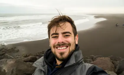 Close-up of cheerful man taking a selfie on Reynisfjara black sand beach in Iceland