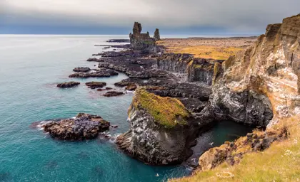 Scenic view of the Lóndrangar cliffs and coastline on the Snæfellsnes Peninsula, Iceland, showcasing rugged rock formations and the vibrant turquoise Atlantic Ocean.