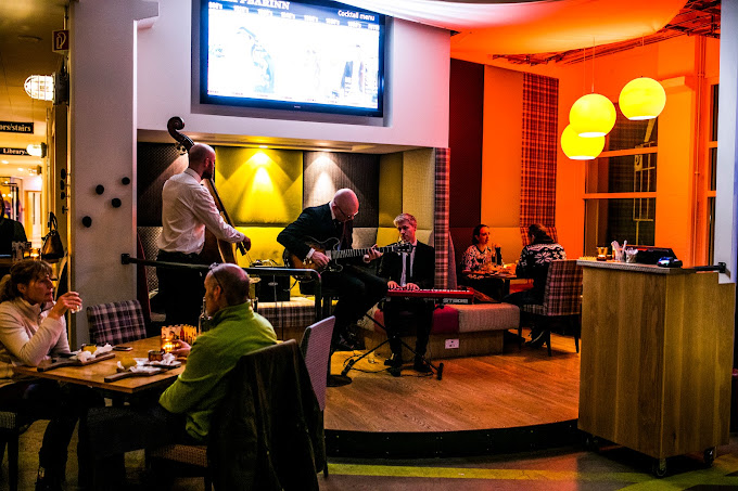 Guests enjoying live jazz music at Slippbarinn bar in Reykjavík, Iceland, with a cozy interior and vibrant atmosphere, offering cocktails and dining options.