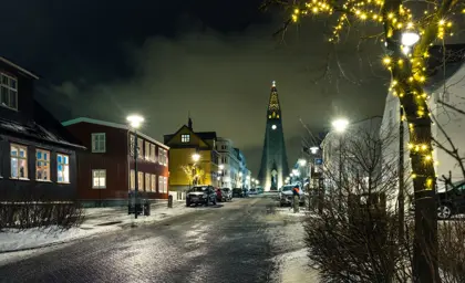 Snowy winter night scene in downtown Reykjavik with twinkling lights and Hallgrimskirkja cathedral towering in the distance