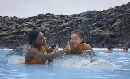 A joyful moment as a family enjoys the geothermal waters of Iceland’s Blue Lagoon, with lush moss-covered lava fields in the background.