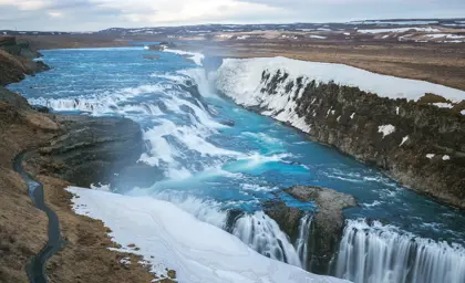 Stunning winter view of Gullfoss Waterfall with icy blue waters cascading down snowy cliffs along the Golden Circle in Iceland