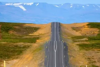 Wavy road from Keflavik to Vik i Myrdal in south Iceland with mountain range in the back.