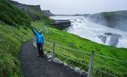 Man taking a selfie with the dramatic Gullfoss waterfall in the background, showcasing the natural beauty of Iceland’s Golden Circle.