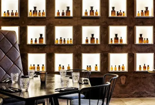 Stylish interior of Apotek Restaurant in Reykjavík, showcasing illuminated shelves with bottles and a chic dining setup, offering a unique dining experience in Iceland.