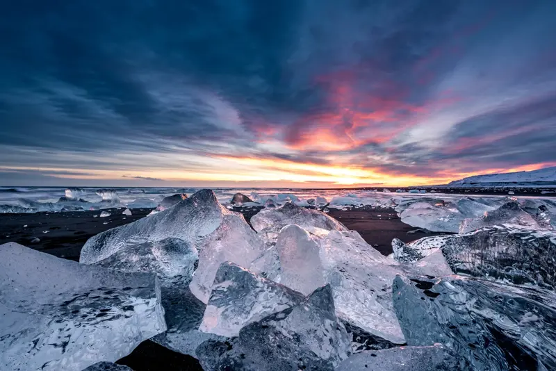 Sunrise at Fellsfjara Diamond Beach with icebergs glistening on the black sand, showcasing Iceland's stunning natural beauty.