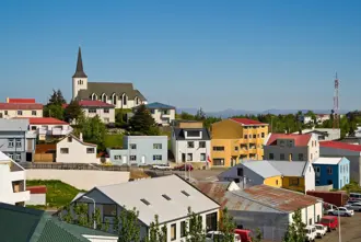Colorful houses and Borgarnes church under a bright blue sky, showcasing the charm of a small Icelandic town, part of a scenic day tour in Iceland.