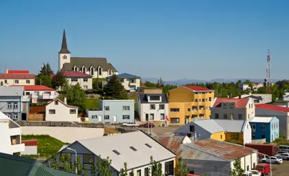 Colorful houses and Borgarnes church under a bright blue sky, showcasing the charm of a small Icelandic town, part of a scenic day tour in Iceland.