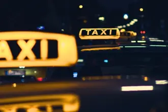 Top of taxis with yellow signs glowing in the dark night. 
