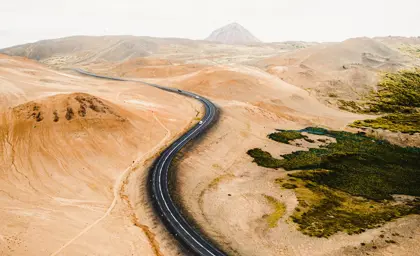 Aerial view of the winding road through the desert-like terrain of Hverfjall, Iceland, highlighting the barren landscape and volcanic surroundings.
