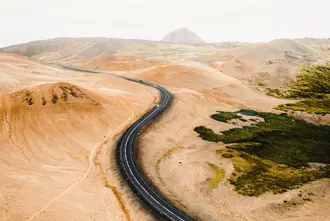 Aerial view of the winding road through the desert-like terrain of Hverfjall, Iceland, highlighting the barren landscape and volcanic surroundings.