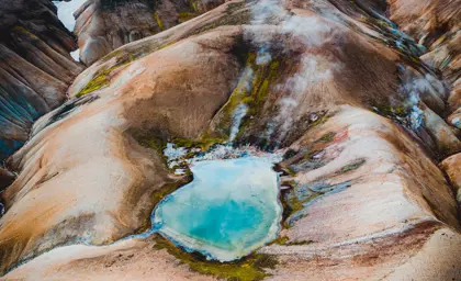 A vibrant blue geothermal pool nestled among colorful mountains in Landmannalaugar.