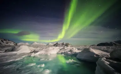 Stunning Northern Lights illuminating the night sky over an icy lagoon in Iceland, showcasing the ethereal beauty of the aurora borealis during a magical winter night tour.