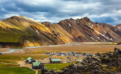 Campsite at Landmannalaugar in Iceland's Highlands, with colorful tents and cabins set against rugged rhyolite mountains.