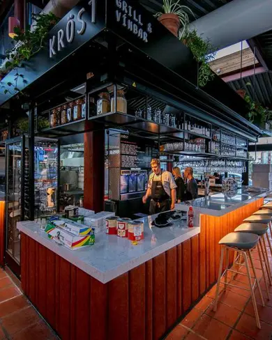 Krost Grill and Wine Bar in Hlemmur Food Hall, Reykjavik, featuring a modern open-bar concept with elegant seating and vibrant evening ambiance.