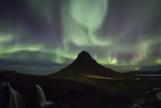 Northern Lights In Iceland Over Kirkjufell Mountain on a dark winter night.