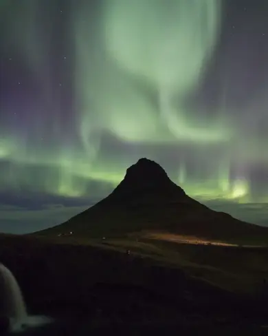 Northern Lights In Iceland Over Kirkjufell Mountain on a dark winter night.