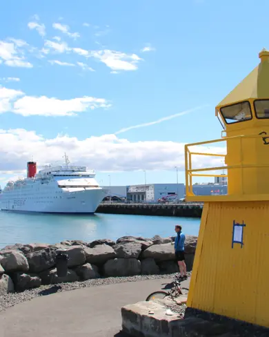 Reykjavík Harbor view of small yellow lighthouse and cruise ship in background.