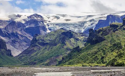 Landscape of Thorsmork in Iceland, with lush green valleys and rugged cliffs framed by a glacier.