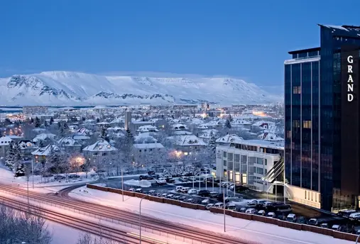 The exterior view of Grand Hótel Reykjavík during winter, with snow-covered surroundings and mountain views.