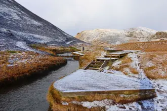 Reykjadalur Hot Spring river surrounded by snow covered ground in winter in Iceland.