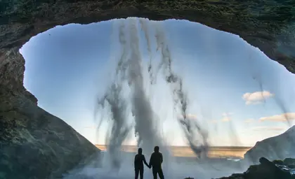 View from behind Seljalandsfoss waterfall where people have walked behind the falls.