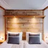 Front view of a wooden four-poster bed with bedside lamps and pillows, creating a warm ambiance at Eyja Guldsmeden Hotel.