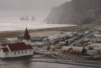 View of Vikurkirkja church, Vik town and Reynisdrangar in winter.