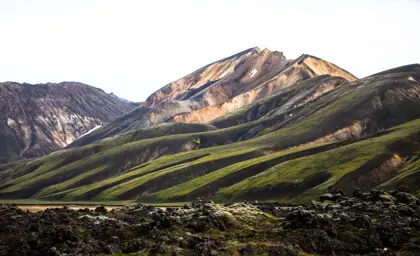The iconic colorful rhyolite mountains of Landmannalaugar with green moss and lava fields in the foreground.