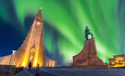Northern lights dancing above Hallgrimskirkja Church and Leif Erikson statue in Reykjavik, Iceland, during a clear winter night.