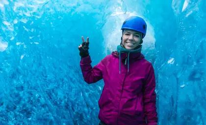 Happy woman inside a glittering blue ice cave during a guided glacier tour in Vatnajökull National Park, Iceland
